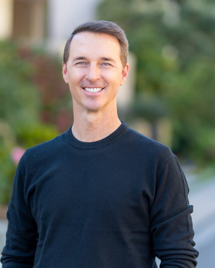 Brad Cook, a Genova founder and principal, standing on a tree-lined residential street.