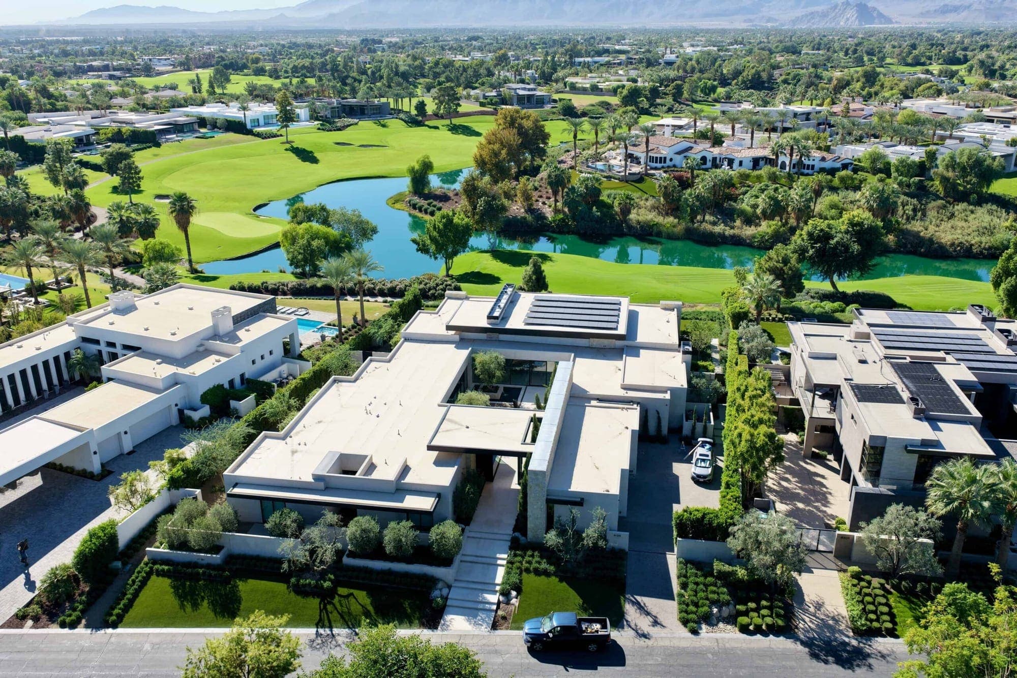 An aerial view of a modern desert estate in La Quinta beside a golf course and lake.
