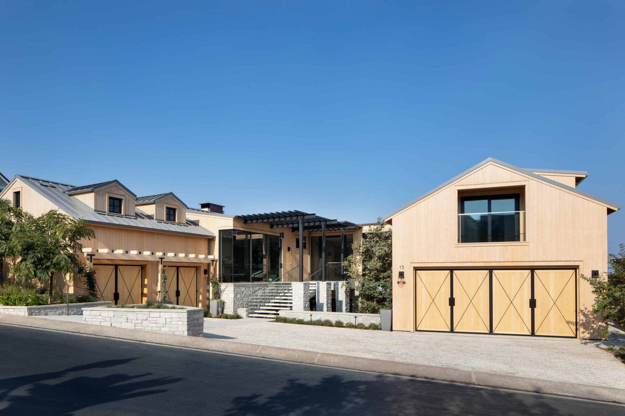 A shingled coastal home in Newport Coast at twilight with a two-car courtyard and warm interior light.