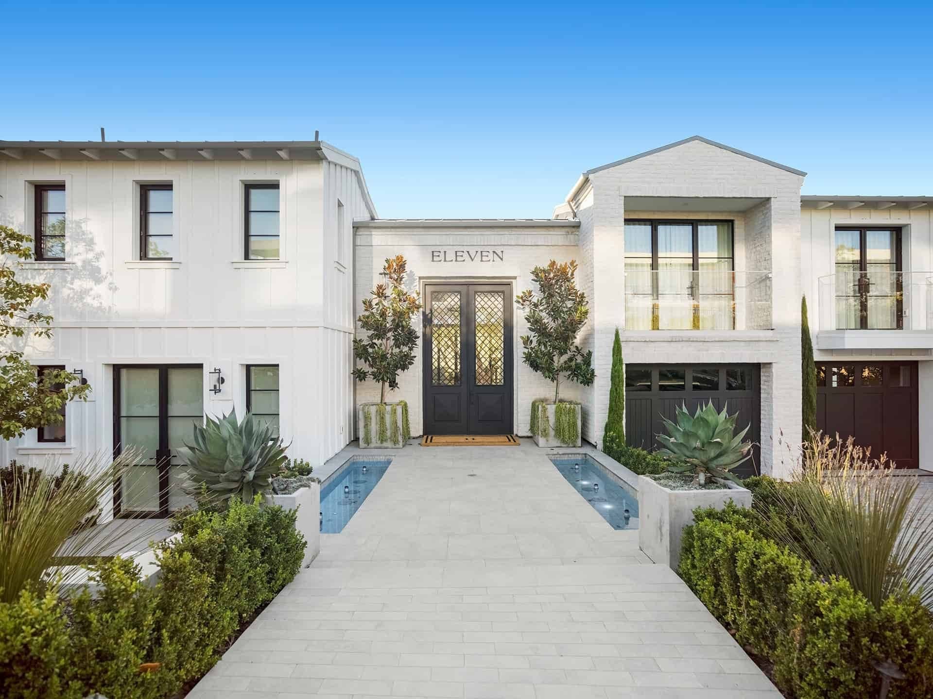 A bright white contemporary home in Dana Point with a soft-lit entry at dusk.
