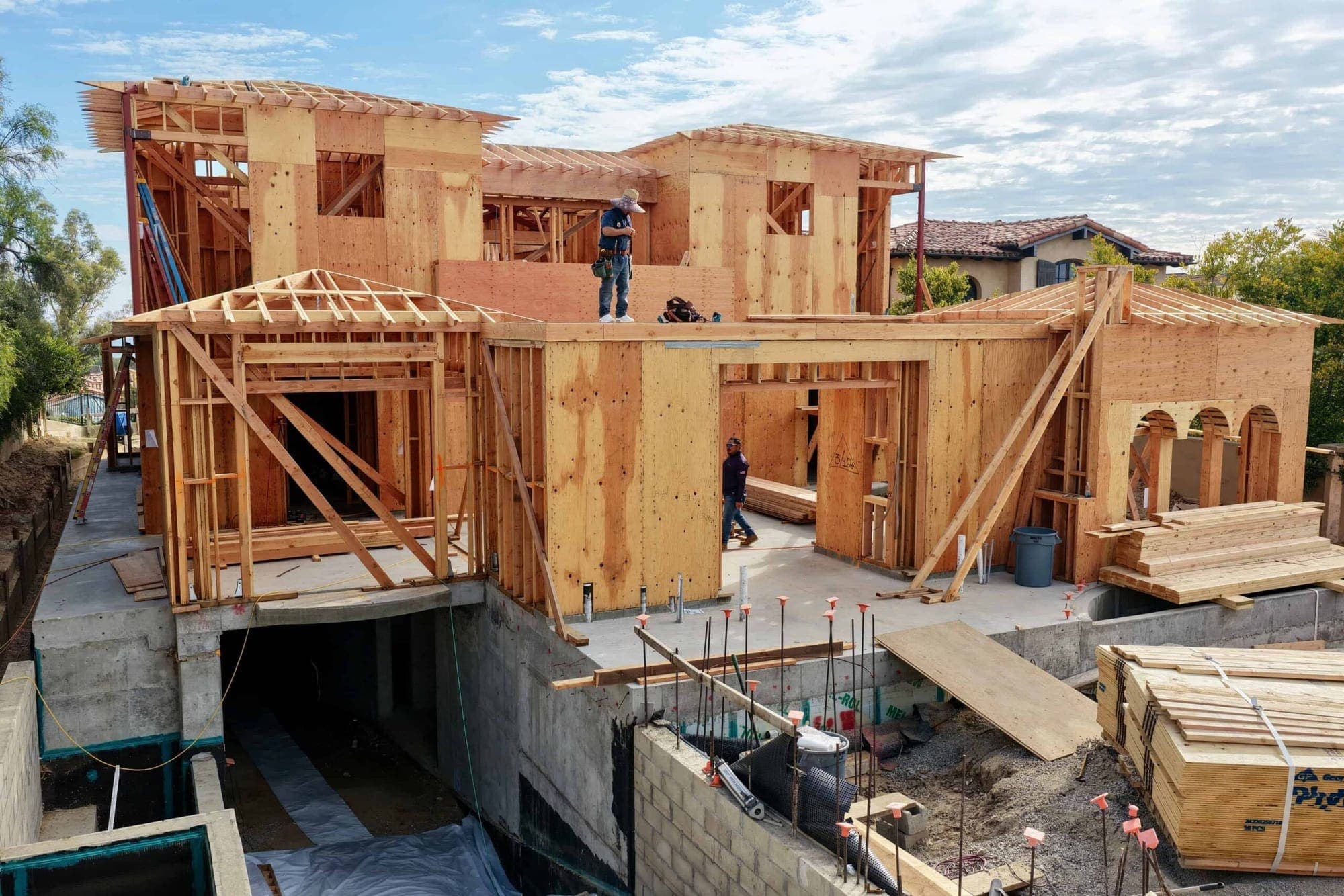 A coastal home under construction on a Newport Coast bluff, framed out with the Pacific behind it.