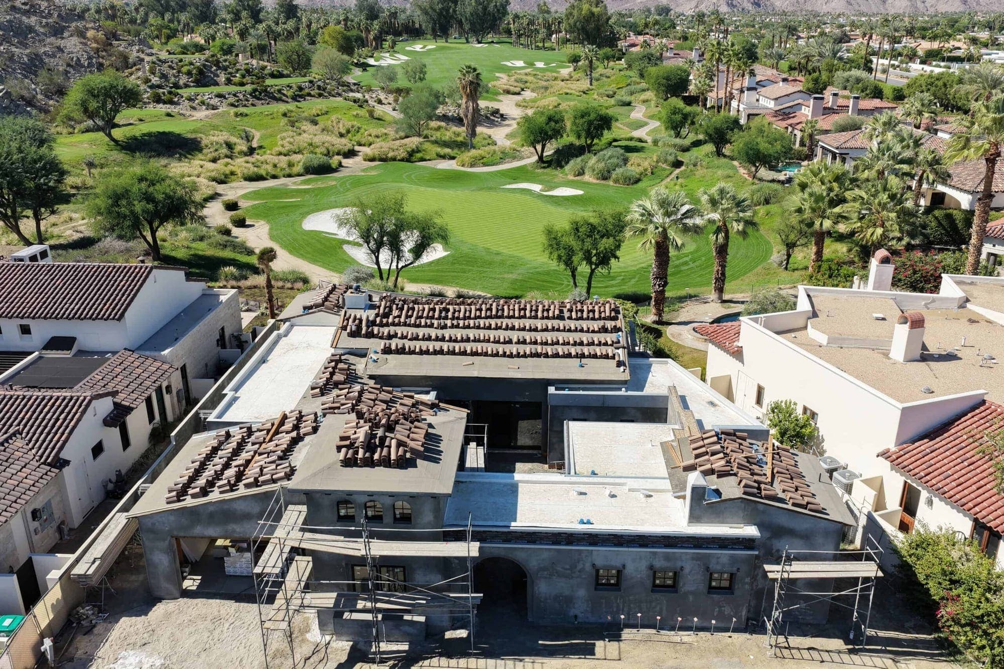 An aerial view of a desert home at Tradition Golf Club in La Quinta among the fairways and mountains.