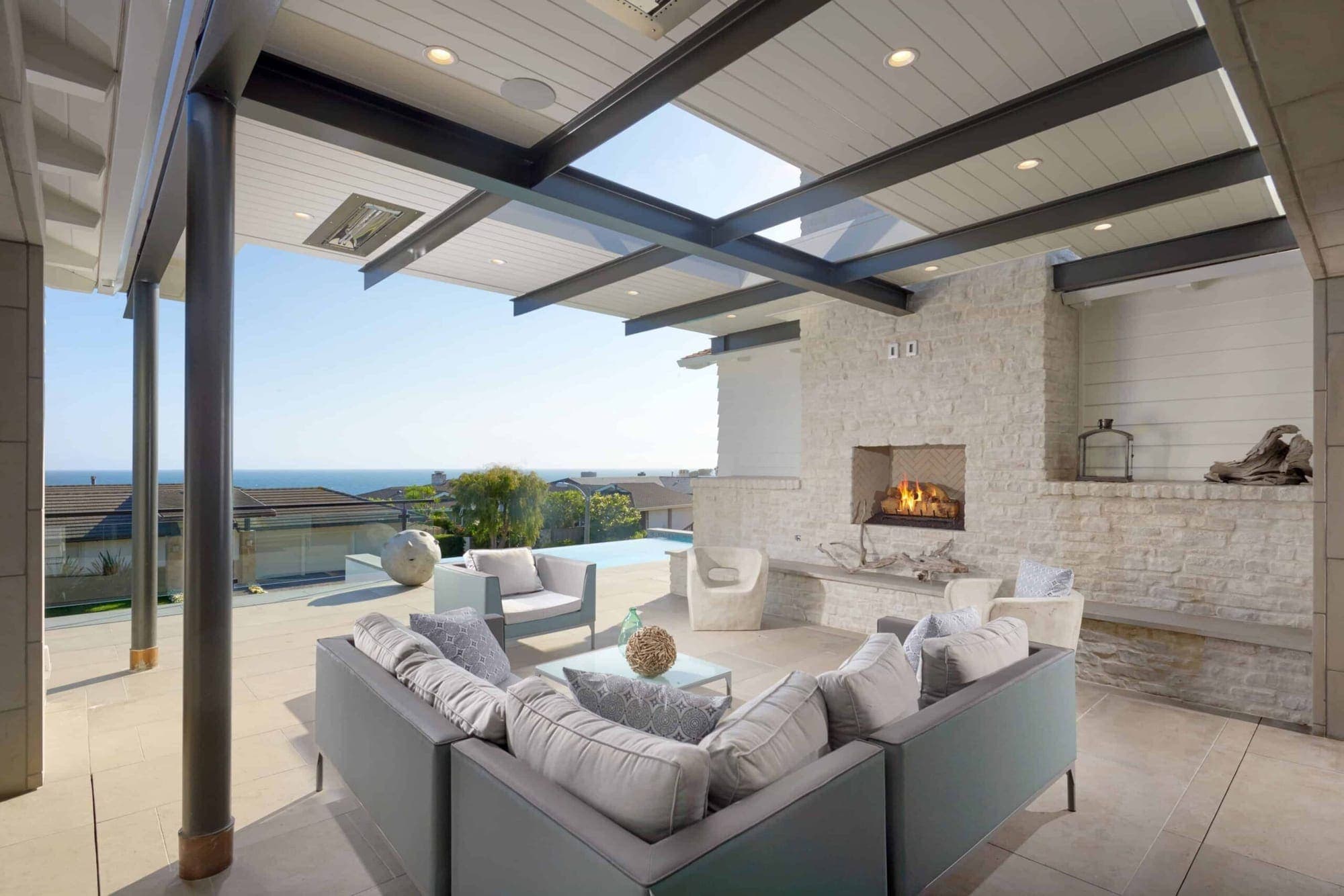 A calm living room with a fireplace set into a full-height stone wall, open to the ocean.